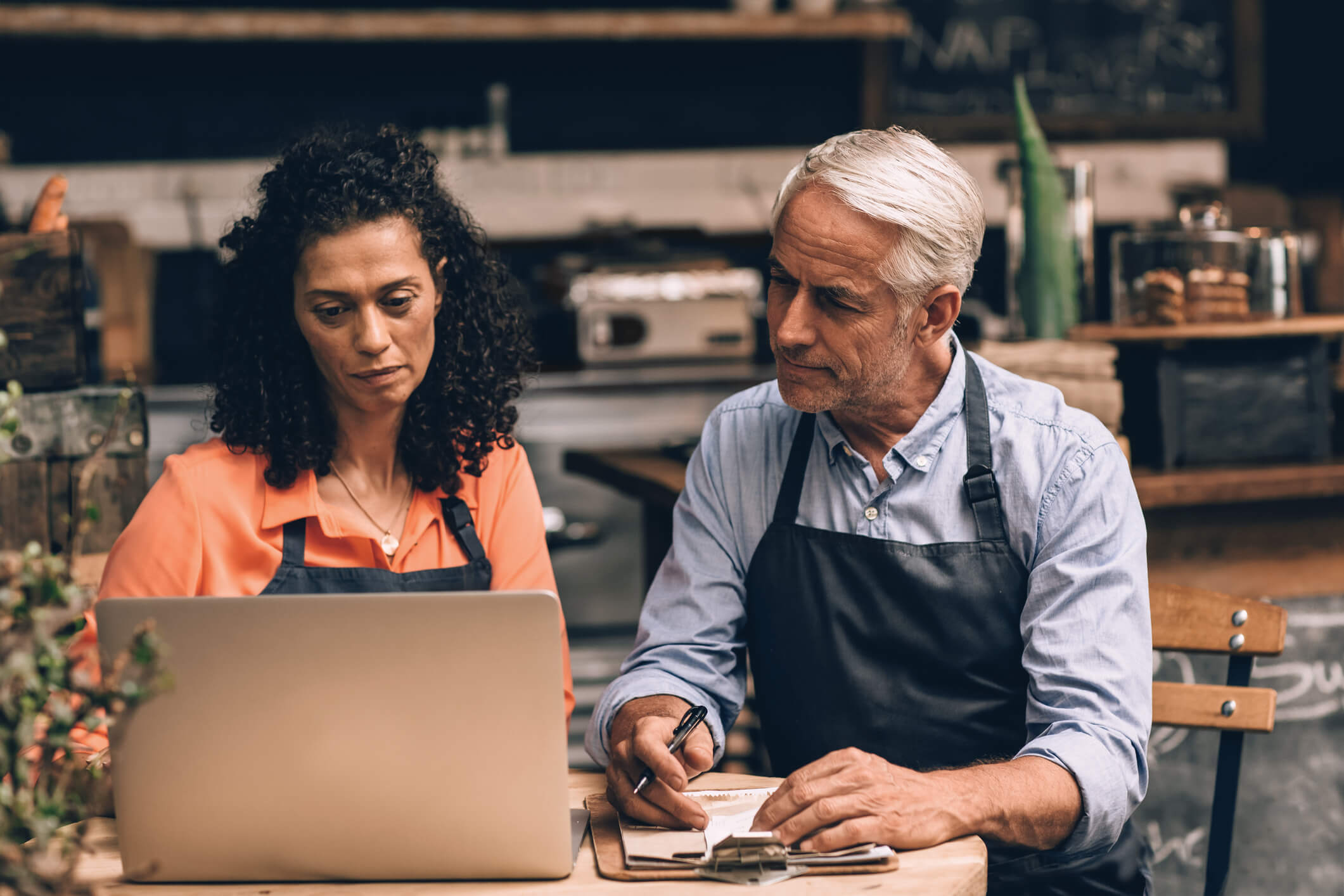 Small business owners wearing aprons looking at computer